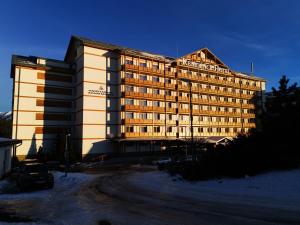 a large hotel building with the sun shining on it at Apartmány IVKA a MAŤKO DONOVALY 198 in Donovaly