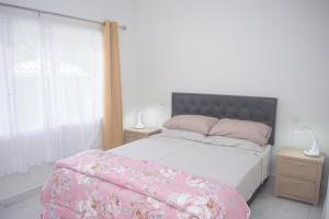 a bedroom with a bed with pink sheets and a window at MOEROA VILLAS in Avatiu
