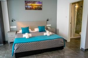 a bedroom with a large bed with blue pillows at A Maos Hotel Apartments in Ayia Napa