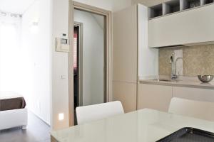 uma cozinha com um balcão branco e cadeiras num quarto em Gioia Maria Sole em Cervia