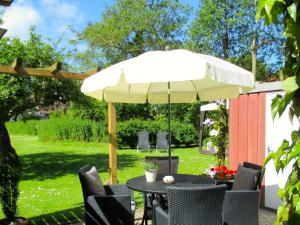 a table and chairs under an umbrella in a yard at Nordsee Haus An't Oll Deep in Dornumersiel