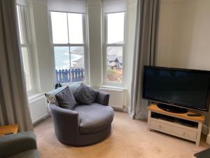a living room with a chair and a flat screen tv at Seacroft in Woolacombe