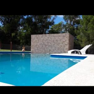 una piscina con agua azul y un tobogán. en La Casona Cabañas en Villa Ciudad Parque