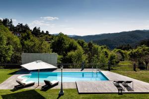 a swimming pool with two chairs and an umbrella at Eira dos Canastros in Sever do Vouga