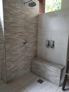 a bathroom with a shower with a stone wall at Rama Shinta Hotel Candidasa in Candidasa