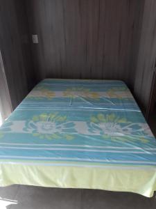 a bed with a blue comforter with flowers on it at Apartamento Sophia 1 in Arraial do Cabo