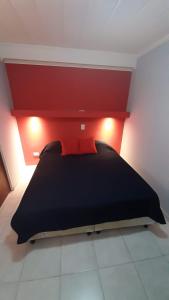 1 dormitorio con cama negra y cabecero rojo en Departamento cómodo, muy iluminado y bien ubicado. en Paraná