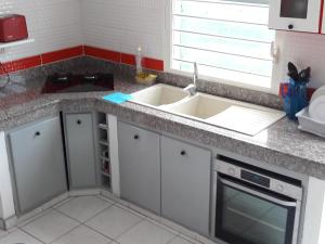 a kitchen counter with a sink and a microwave at Duplex La Rivière in Deshaies