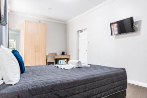 福斯特Lakes and Ocean Hotel Forster的一间卧室，有一张床，墙上有一台电视 更多22张照片