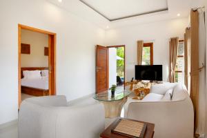 Una sala de estar con un sofá, una mesa y una cama. en Askara Villa Uluwatu, en Uluwatu