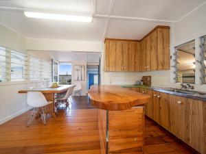 a kitchen with wooden cabinets and a wooden table at Ahoy Cottage by Discover Stradbroke in Point Lookout +7 photos