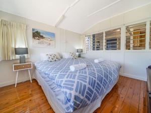 a bedroom with a bed with a blue and white comforter at Ahoy Cottage by Discover Stradbroke in Point Lookout