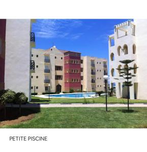a group of buildings with a tree in the grass at TANGER/ASILAH: APPART 50m2 FACE MER ET PISCINES, 5 PLACES, TOUT ÉQUIPÉ+WIFI+CLIM in Briech
