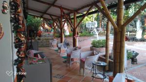 a patio with white chairs under a wooden pergola at Casa guadua piscina privada in La Mesa