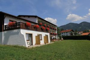 un edificio con un balcón con flores rojas. en Hotel Alpenblick Berghof en Halblech-Buching