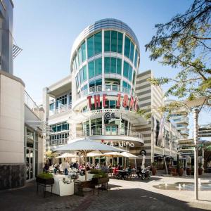 a building with tables and umbrellas in front of it at Luxury Stay Rosebank Johannesburg in Johannesburg