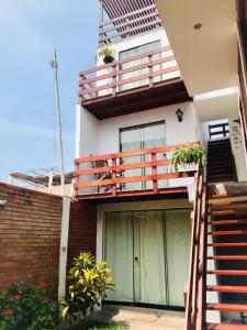 a house with a balcony and stairs and flowers at Casa de Playa Arica in Lurín