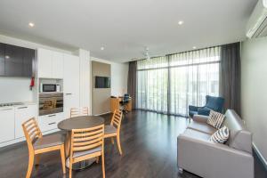 a kitchen and a living room with a table and a couch at Mawson Lakes Hotel in Adelaide