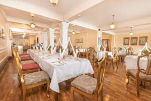 un comedor con mesas y sillas blancas en The Elgin Mount Pandim - Heritage Resort & Spa en Pelling