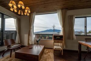 a living room with a large window and a table and chairs at Villa Fuji Bon Voyage Mori in Fujikawaguchiko