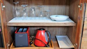 a cabinet with a red tea kettle and glasses at THE TIN SHED Couples accommodation at Bay of Fires in Binalong Bay