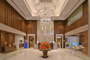 a lobby with a large chandelier and a vase of flowers at Golden Sarovar Portico in Amritsar