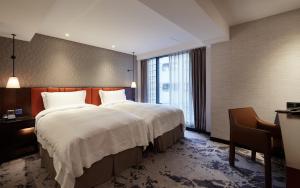 una camera d'albergo con un grande letto e una finestra di Tango Inn Taipei ZhongShan a Taipei