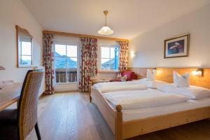 1 dormitorio con 1 cama, escritorio y ventanas en Hotel-Garni Schernthaner, en Sankt Gilgen