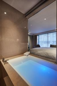 a bath tub in a bedroom with a bed at Tango Inn Taipei ZhongShan in Taipei