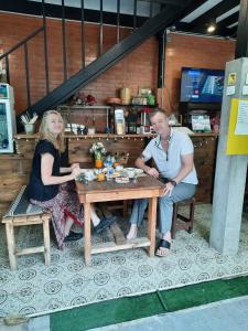 Green Teak House في بانكوك: رجل وامرأة يجلسون على طاولة خشبية