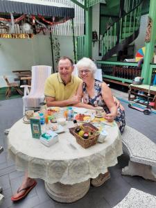 Ein Mann und eine Frau sitzen an einem Tisch mit Essen in der Unterkunft Green Teak House in Bangkok