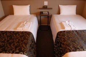 2 Betten in einem Hotelzimmer mit Handtüchern darauf in der Unterkunft PORTA INN bentencho in Osaka