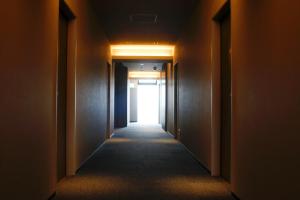 an empty hallway with a light at the end at PORTA INN bentencho in Osaka