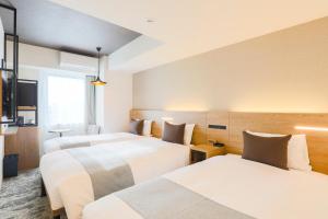 a hotel room with three beds and a tv at Hotel Wing International Sapporo Susukino in Sapporo