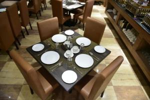 a black table with white plates on it in a restaurant at Hotel Crystal Grand in Haldwāni