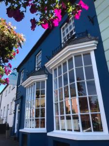 um edifício azul com janelas brancas e flores cor-de-rosa em The Blue Mantle em Wellington