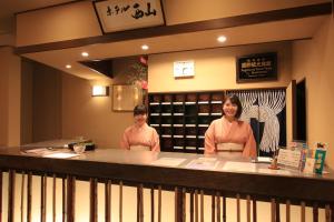 two women standing behind a counter in a salon at Nishiyama Ryokan - 1953年創業 in Kyoto