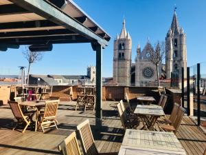 a patio with tables and chairs and a church at Camarote Hotel in León