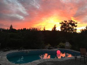 um pôr-do-sol sobre uma piscina num quintal em Gite Les Pignons em Roquebrune