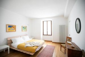 a white bedroom with a bed and a table at IseoLakeRental - Borgo Lago in Riva di Solto