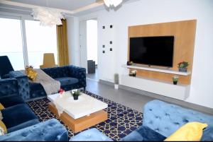 a living room with blue furniture and a flat screen tv at West ghammarth garden1 in Borj el Khessous