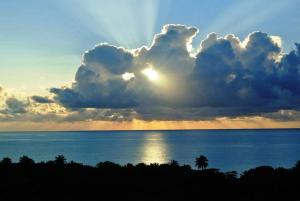 una puesta de sol sobre el océano con el sol escondido detrás de una nube en Sunrise Villa, en Maunabo