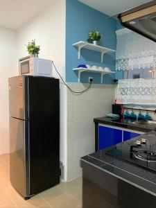 cocina con nevera negra y paredes azules en Garden Sky Homestay en Melaka