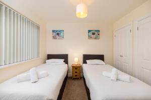 two beds in a room with white sheets at West Beach - Holiday Apartments in Westward Ho
