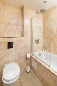 y baño con aseo, ducha y bañera. en West Beach - Holiday Apartments en Westward Ho