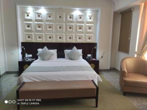 ein Schlafzimmer mit einem großen Bett und einem Stuhl in der Unterkunft Conference Hotel , Abeokuta in Abeokuta