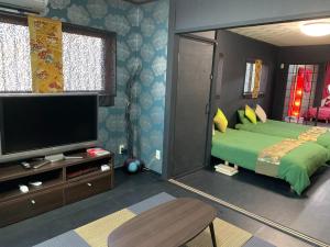 a bedroom with a large green bed and a flat screen tv at Maximum of 18 people can be rented in one building 3 minutes walk to Tomari Port 10 minutes drive to the airport No parking lot 30 seconds walk from paid parking lot warayunso port city May in Naha