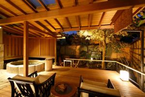 un patio con una terraza de madera con sillas y una bañera de hidromasaje. en Yumeguri no Yado Yoshiharu en Izunokuni