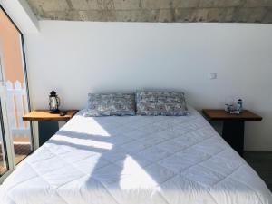 a bedroom with a white bed with two tables at CASA DO MAR in Jardim do Mar