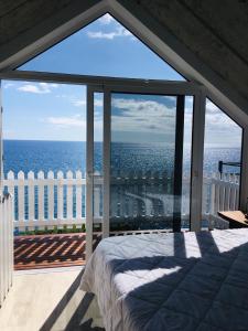 1 dormitorio con vistas al océano desde el balcón en CASA DO MAR, en Jardim do Mar